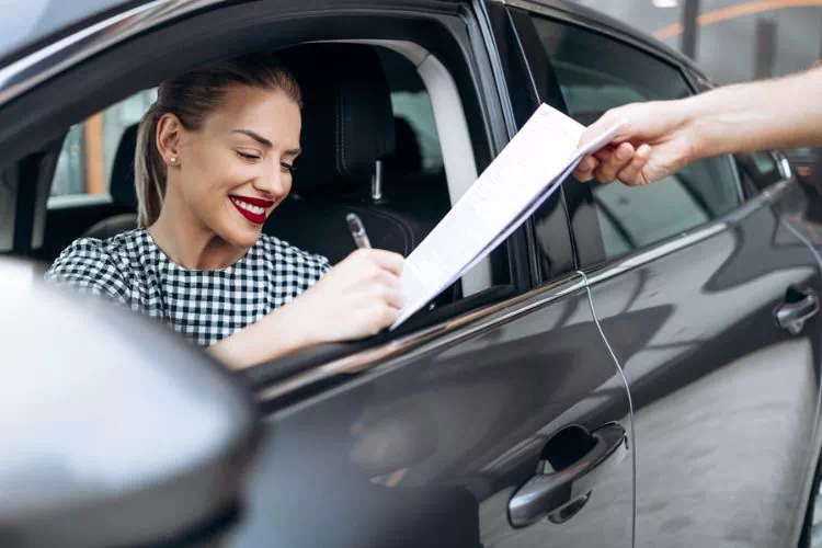 Femme en train de signer le contrat de vente d'un véhicule