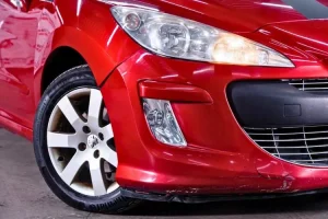 Peugeot 308 rouge dont le pare-choc est abîmé