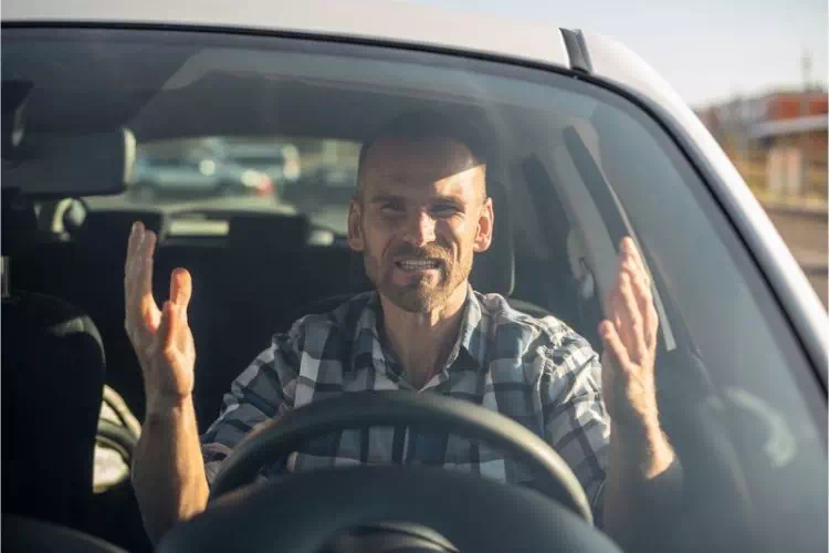 Homme énervé au volant à cause d'un pneu éclaté